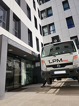 Camião LPM Rent com plataforma elevatória em frente a um edifício para manutenção e limpeza de fachadas em Carregado - Serviços de elevação e aluguer de equipamentos